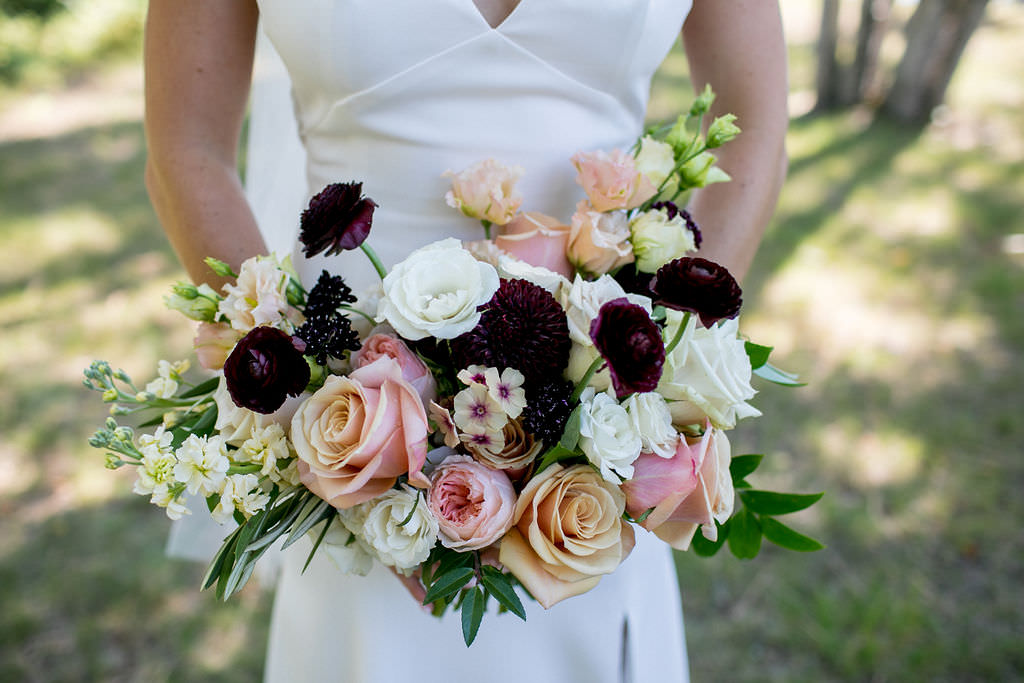 Bridal bouquet with peach, pink, ivory, and burgundy flowers 