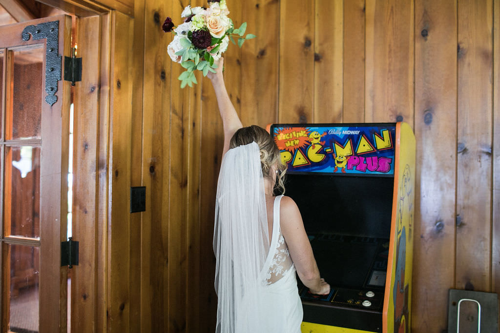 Bride with bouquet playing Pacman at a Montana wedding venue