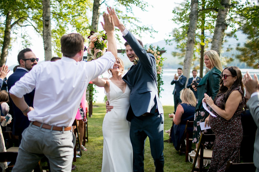 Bride, groom, and guest high fiving after the ceremony at a Montana wedding venue