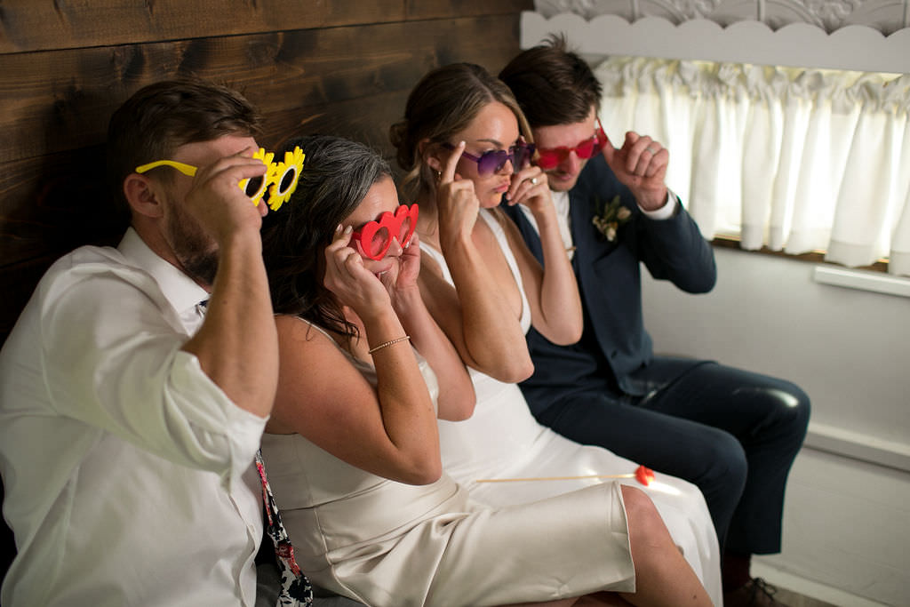 Guests posing for photo booth with glasses at Six Mile Estate, a Montana wedding venue