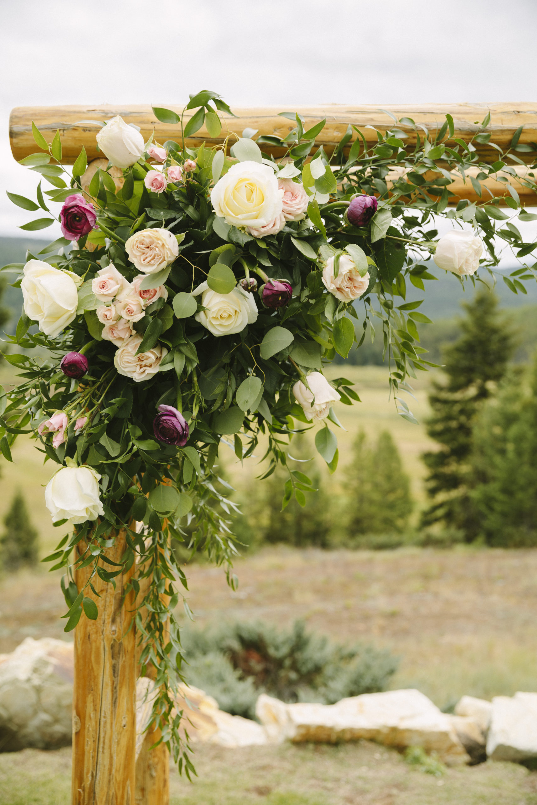 Pink and white floral spray on wooden arch for a ranch wedding ceremony